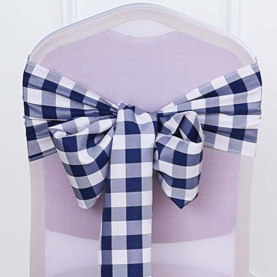 Navy and white checkered chair sash tied in a bow on a transparent chair.