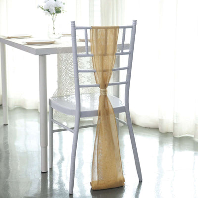 White chair with gold ribbon draped over the back, set near a table in a bright room.