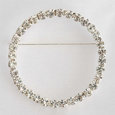 Circular rhinestone brooch with sparkling crystals on a silver pin.