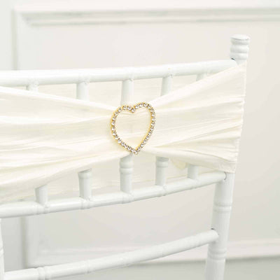 White chair sash with heart-shaped rhinestone embellishment.