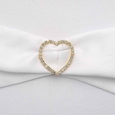 Gold heart-shaped brooch adorned with rhinestones on white fabric