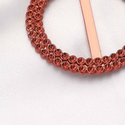 Red rhinestone circle brooch on a soft fabric background.