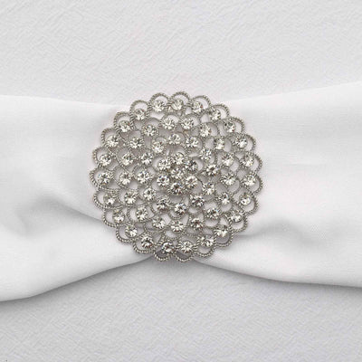 Silver floral brooch with rhinestones on white fabric