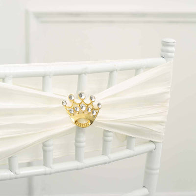 Gold crown chair sash decoration with rhinestones on white chair.