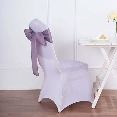 Purple satin bow on a white chair cover against a plain background.