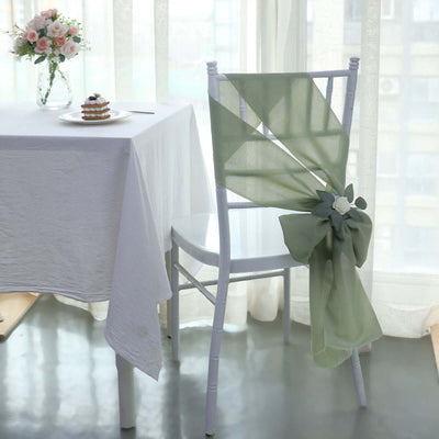 Elegant green chair sash decoration on a white chair in a bright dining setting.