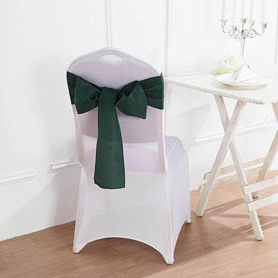 White chair cover with green bow, perfect for events and weddings.