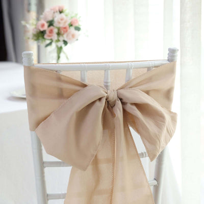 Beige satin chair sash tied in a bow on a white chiavari chair.