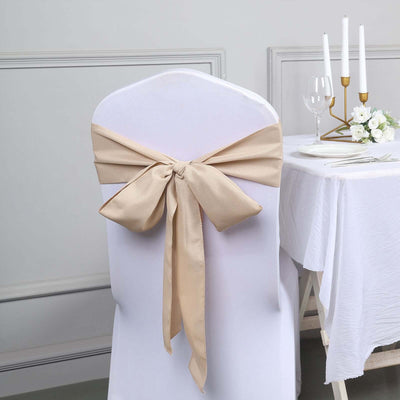 Beige chair cover bow on a white chair at an elegantly set dining table.