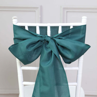Teal satin chair sash tied in a bow on a white chiavari chair.