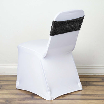 White chair with a black sequined sash on a plain background.