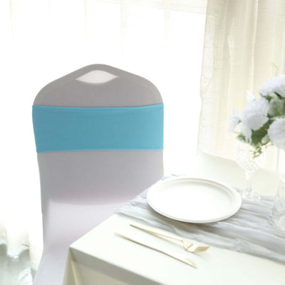 Blue chair cover on a white dining chair by a table with a plate and flowers.