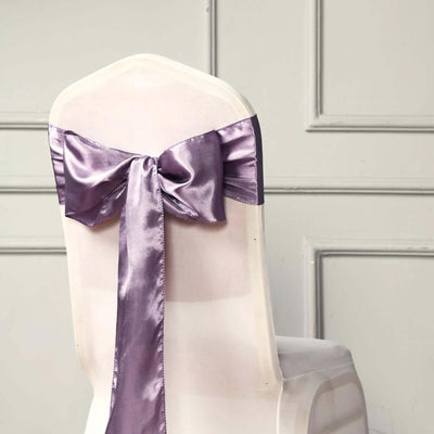 Purple satin chair sash tied in a bow on a white chair.