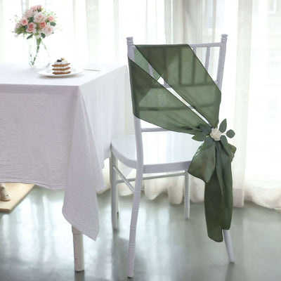 Elegant green chair sash draped on a white chair in a bright dining setting.
