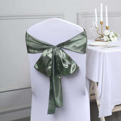 Green satin chair sash tied on a white chair at a dining table.