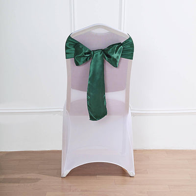 White chair cover with green satin bow, perfect for event decor.