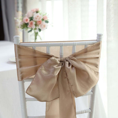 Elegant champagne satin chair bow tied on a white chair.