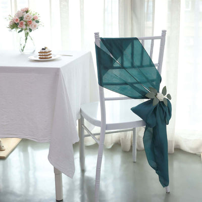 Teal chair sash with floral accent draped over a white chair in a dining setting.