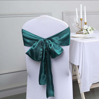 Teal satin chair sash tied on a white chair in a dining setup.