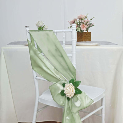 Green satin chair sash with a rose accent on a white chair.