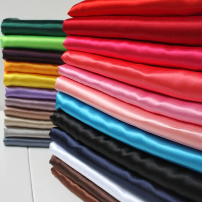 Stack of colorful fabric rolls in various shades and textures.