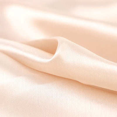Peach satin fabric draped elegantly, showcasing smooth texture and sheen.