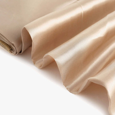 Beige satin fabric draped gracefully on a white background.