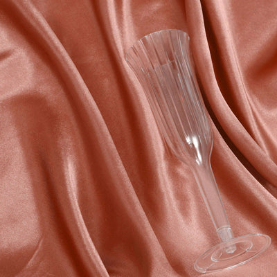 Clear fluted champagne glass on soft satin fabric.