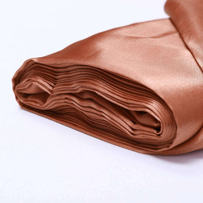 Rolled satin fabric in warm brown color on a plain background.