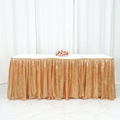 Gold sequin table skirt with floral centerpiece on a white table.