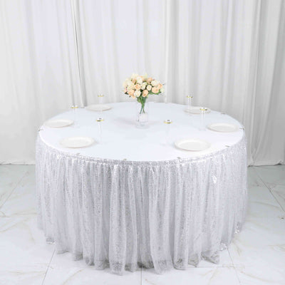 Round table with silver sequin tablecloth and floral centerpiece.