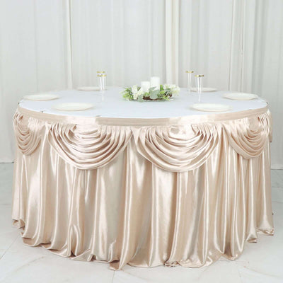 Elegant round table with draped champagne satin tablecloth and floral centerpiece.