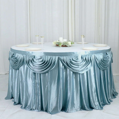 Elegant round table with a satin blue tablecloth and floral centerpiece.