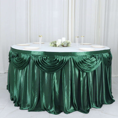Round table with elegant green satin tablecloth and decorative draping.