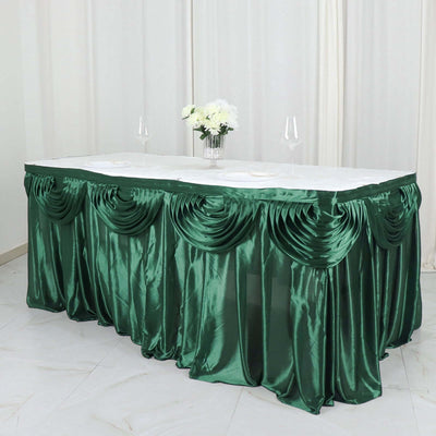 Green satin table skirt with elegant draping, perfect for events and banquets.