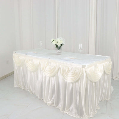 Elegant white table with draped satin tablecloth and floral centerpiece.