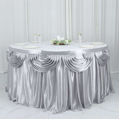 Round table with elegant silver satin tablecloth and decorative draping.