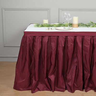 Burgundy table skirting with elegant table setting and greenery decor