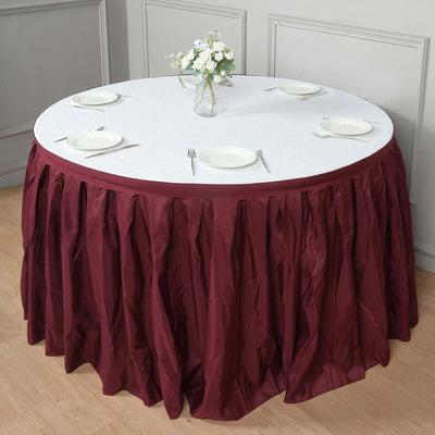 Round burgundy tablecloth draping elegantly over a table set for dining.