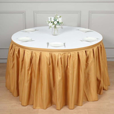 Round table with gold skirt and white tablecloth, set for dining with plates and cutlery.