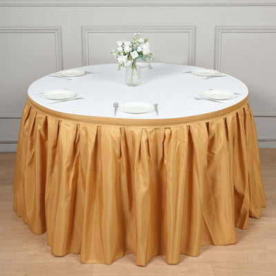 Round table with golden skirt and white tablecloth, set for dining.