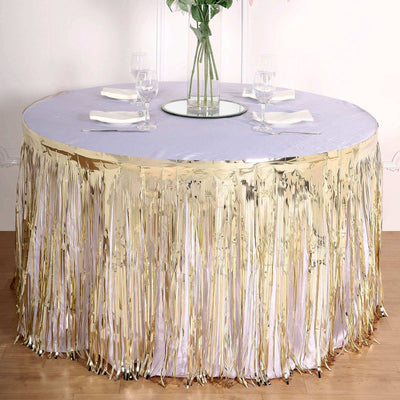 Round table with gold fringe skirt and mirrored center, elegantly set for dining.