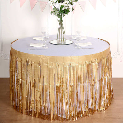 Gold fringed table skirt on a round table with floral centerpiece.