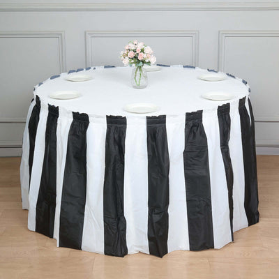 Black and white striped table cover on a round table with plates and flowers.