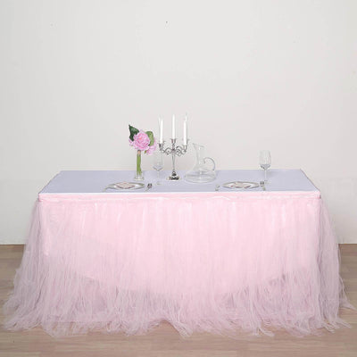 Elegant pink tulle table skirt with white tablecloth and decorative centerpiece.