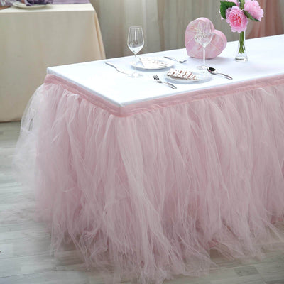Pink tulle table skirt draped elegantly on a white table setting.