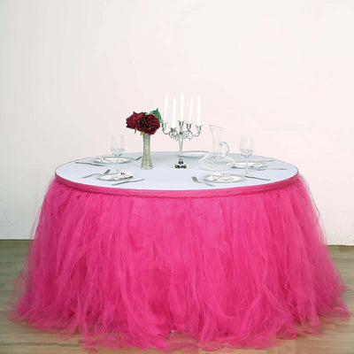 Pink tulle table skirt with elegant dining setup and floral centerpiece.