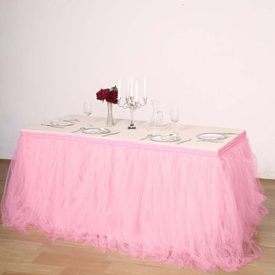 Pink tulle table skirt draped over a dining table with elegant tableware.