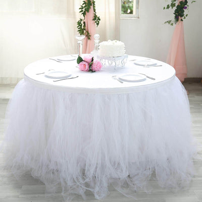 Round table with white tulle skirt and floral centerpiece in elegant setting.