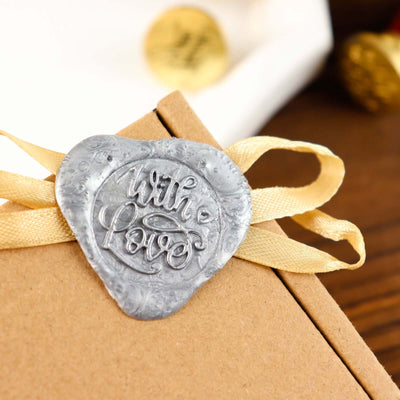 Wax seal with "With Love" on a gift box, adorned with a ribbon.